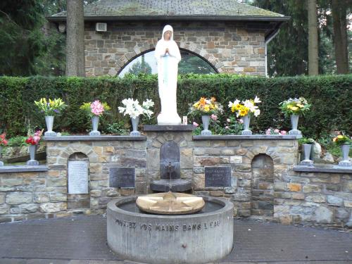 Eine Statue einer Frau, die auf einem Brunnen steht. in der Unterkunft Hotel Halleux in Banneux