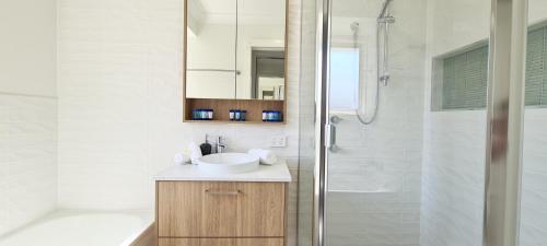 a white bathroom with a sink and a shower at Weeroona on Nulu in Bongaree