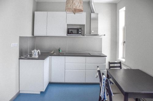 a kitchen with white cabinets and a table and a dining room at Hostel Nr.2 in Rauna