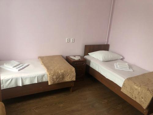 a room with two beds and a night stand with two beds at Zhemchuzhina Kavkaza Hotel in Zheleznovodsk
