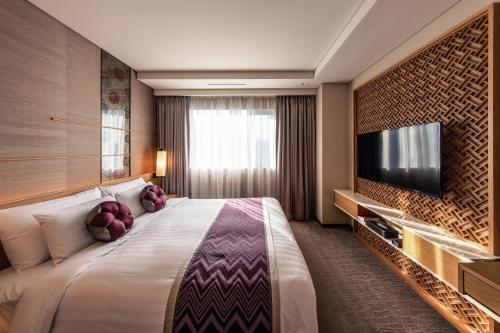 een hotelkamer met een groot bed en een flatscreen-tv bij Royal Hotel Seoul in Seoul