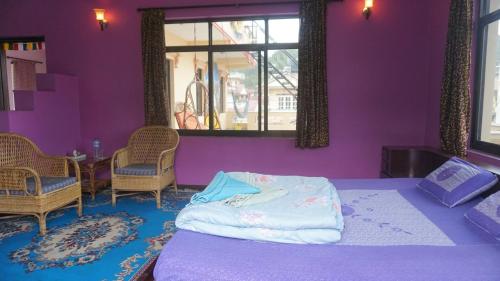 a bedroom with purple walls and a bed with chairs at Monkey Bunky-3Monkeys Backpacker's Hostel in Kathmandu