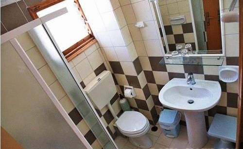 een kleine badkamer met een wastafel en een toilet bij Sunlight Hotel in Agia Galini