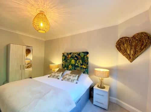 a bedroom with a white bed with a heart on the wall at Meadfoot Bay Apartment at Hesketh Crescent in Torquay
