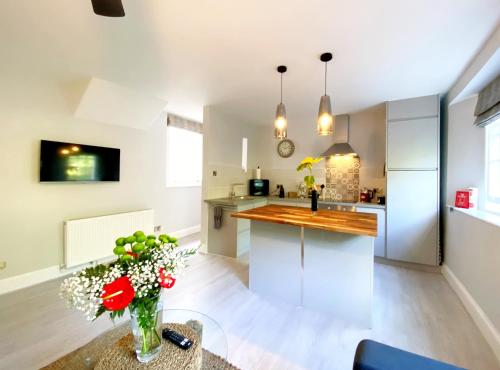 a kitchen with a vase of flowers on a table at Meadfoot Bay Apartment at Hesketh Crescent in Torquay