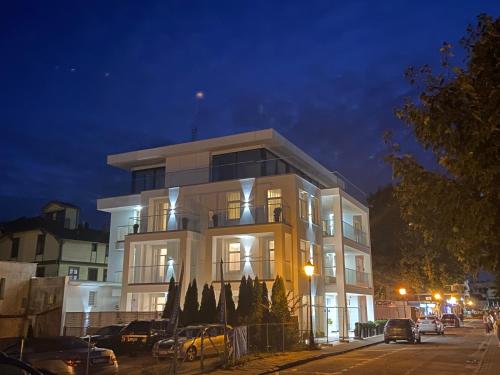 un gran edificio blanco por la noche con coches aparcados delante en Residence Puro Beach - Adults only, en Międzyzdroje