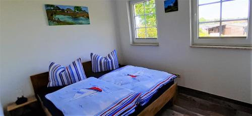1 Schlafzimmer mit einem Bett mit blauer Bettwäsche und 2 Fenstern in der Unterkunft Ferienwohnung Alter Fischerhof in Malchow