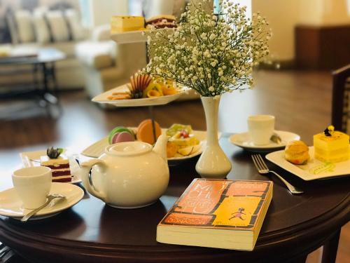 a table with a tea pot and a vase of flowers at The Tray Hotel Hai Phong in Hai Phong