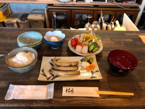 una tavola con piatto di cibo e ciotole di riso di Guesthouse & Kitchen Hace a Iwaki