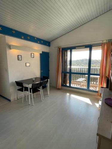 une pièce avec une table et des chaises et une grande fenêtre dans l'établissement T2 mezzanine Seignosse Océan plein coeur du Penon, à Seignosse