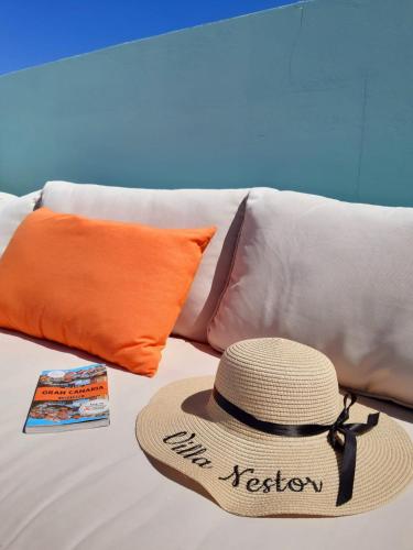 a straw hat sitting on a couch with pillows at Villa Nestor in Ingenio