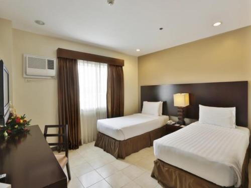 a hotel room with two beds and a television at Alpa City Suites Hotel in Cebu City