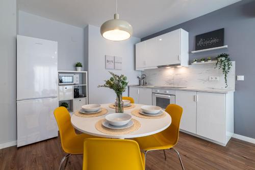 a kitchen and dining room with a table and yellow chairs at Apartamento Luis de Vargas in Huelva