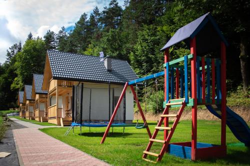 a playground with a slide and a house at Domki na Zaciszu in Lesko