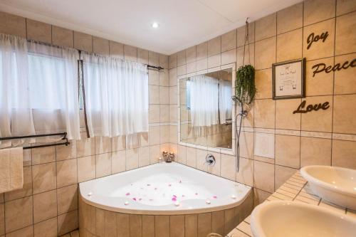 a bathroom with a bath tub and a sink at Winterton Country Lodge @ Rose Cottage in Winterton