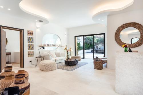 a living room with white walls and a large mirror at Hotel delle Rose a Luxury Boutique Hotel in Porto Cervo
