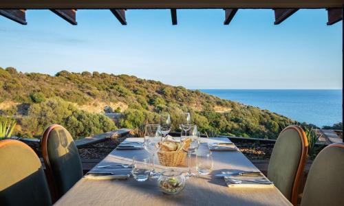 a table with wine glasses and a basket on it at Eco Village Baia Delle Ginestre in Teulada