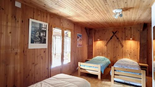 1 dormitorio con 2 camas y pared de madera en APPARTEMENT-3-CHAMBRES-8-COUCHAGES-WIFI-MONTRIOND-CHEBOURINS, en Montriond