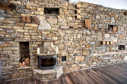 a stone wall with a fireplace in a room at ТАНГЕНТА стаи за гости in Oreshak