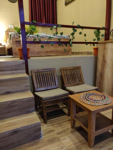 two chairs and a table in a room with stairs at Chamba Nest in Chamba