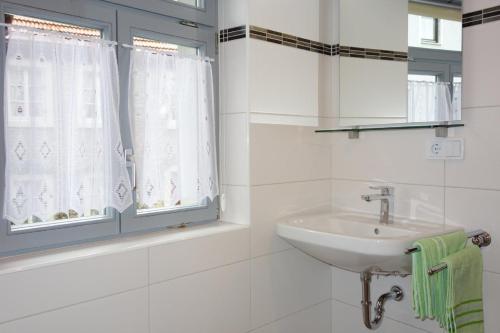 ein weißes Badezimmer mit Waschbecken und Fenster in der Unterkunft Ferienwohnung Häckerstub'n Zang in Sommerach
