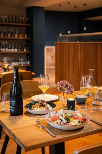 a wooden table with two plates of food and a bottle of wine at Nineofive Hotel in Jena