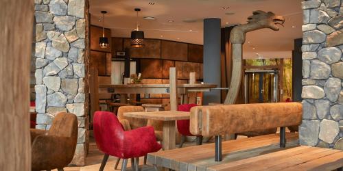 a restaurant with tables and chairs and a stone wall at Ostseehotel Midgard in Damp in Damp