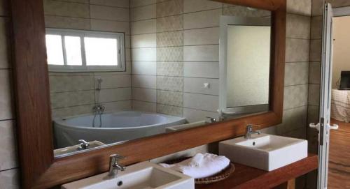 La salle de bains est pourvue d'une baignoire, de 2 lavabos et d'un miroir. dans l'établissement Sahamalaza, à Ivato