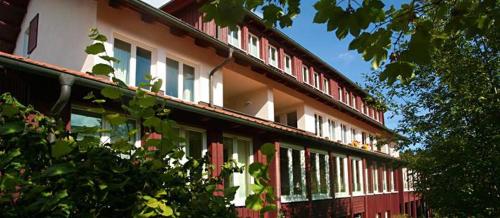 a red and white building with windows and trees at Wintergartenhaus Braunlage in Braunlage