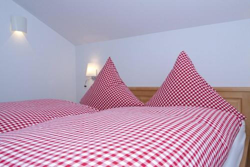 un letto rosso e bianco con lenzuola a scacchi rosse e bianche di Ferienhaus Alpenflair bei Schliersee a Schliersee