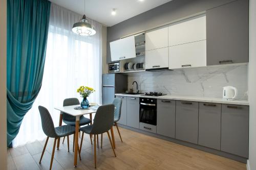 a kitchen with white cabinets and a table and chairs at Двух комнатная квартира в центре in Mykolaiv