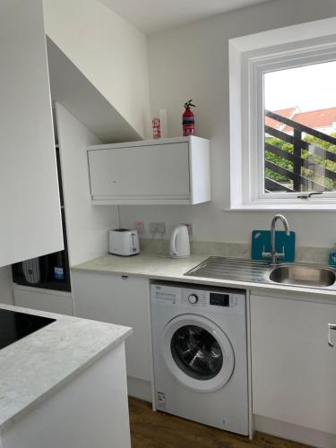cocina blanca con lavadora y ventana en Albert Road Apartment, en Eyemouth