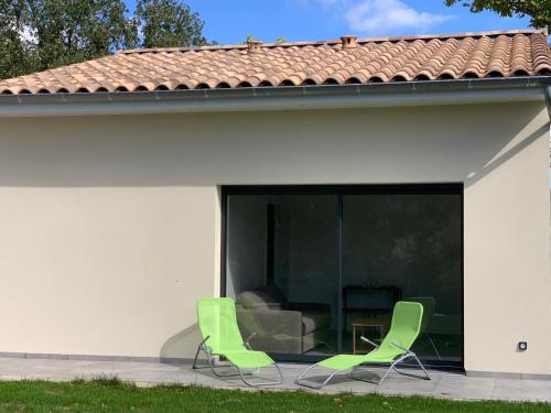 - deux chaises vertes assises sur une terrasse à côté d'une maison dans l'établissement ENTRE RIVIERE ET FORET, à Vallon-Pont-dʼArc