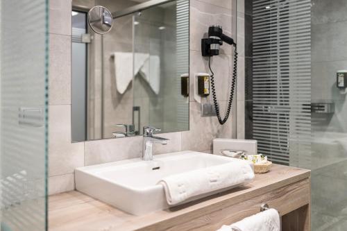 a bathroom with a white sink and a mirror at Familienhotel Post in Millstatt