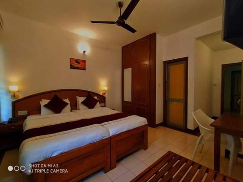 1 dormitorio con 1 cama grande y ventilador de techo en KTDC Tamarind, Mannarkkad, en Alanallūr