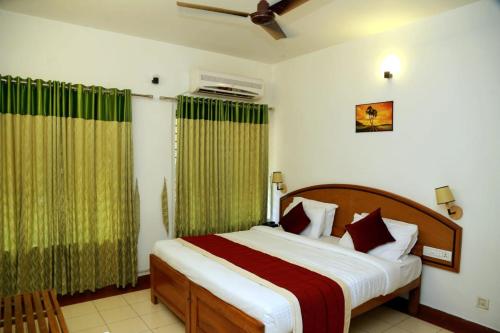 1 dormitorio con 1 cama grande y cortinas verdes en KTDC Tamarind, Mannarkkad, en Alanallūr