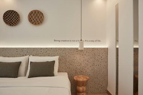 a bedroom with a white bed and a wall at Kosmoplaz Beach Hotel in Platis Yialos Mykonos
