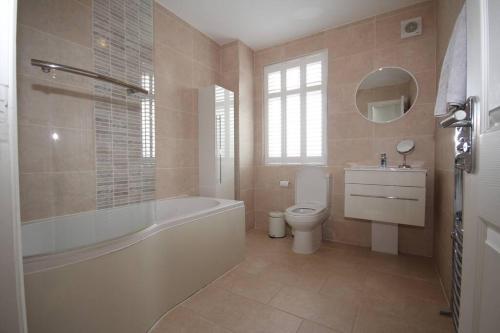 a bathroom with a tub and a toilet and a sink at Harrow Place- Stylish Two Bedroom Apartment. in Harrow