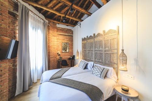 a bedroom with a large bed and a brick wall at Hotel La Casa de Los Mosaicos by Maxi Hoteles in Granada