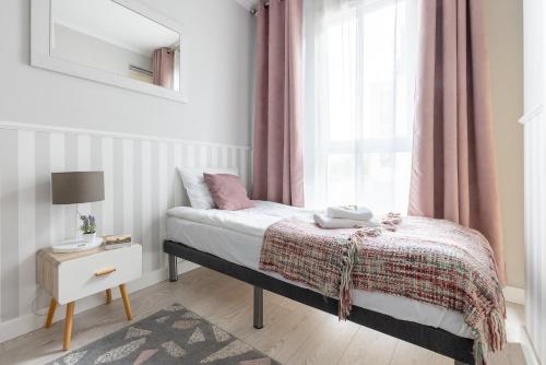 a small bedroom with a bed and a window at INA Rent - Tre Mare Apartamenty in Gdańsk