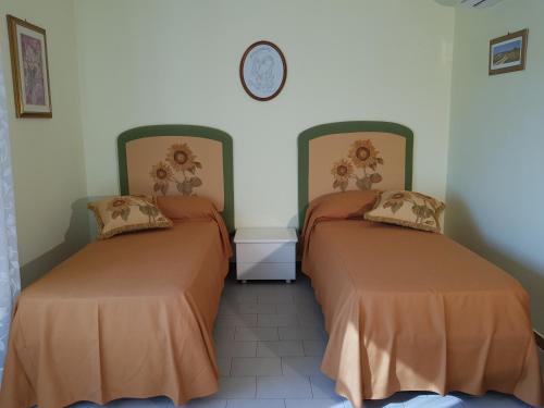 two beds in a room with a clock on the wall at Top bedroom GOLFO - Le Lincelle, Lamezia - 2 extra large single beds in SantʼEufemia Lamezia