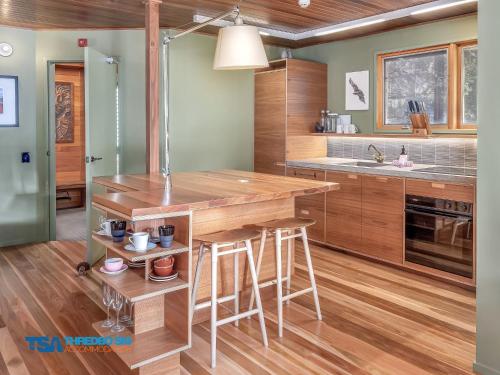 a kitchen with a wooden island with stools at Milkwood 3 Chalet in Thredbo