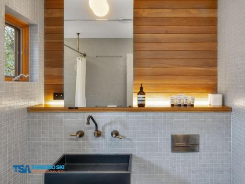 a kitchen with a sink and a mirror at Milkwood 3 Chalet in Thredbo