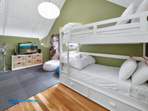 a bedroom with two bunk beds and a tv at Milkwood 3 Chalet in Thredbo