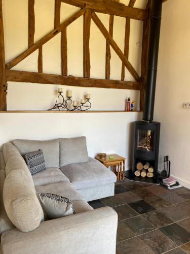 a living room with a couch and a wood stove at The Hop Barn in Staplehurst