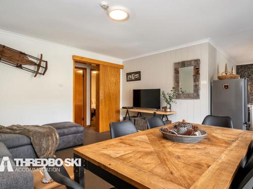 a living room with a wooden table and a couch at Mowamba E2 in Thredbo