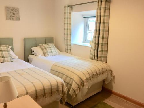 a bedroom with two beds and a window at Cosy Cottages in Llandeilo