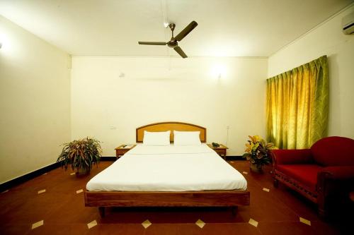 a bedroom with a bed and a red couch at KTDC Tamarind, Nilambur in Nilambūr