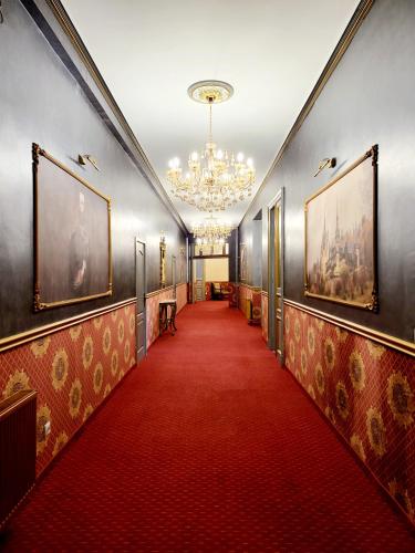 a hallway with a red carpet and a chandelier at NF Palace Old City Bucharest in Bucharest