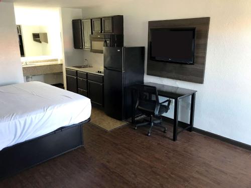 a hotel room with a bed and a desk and a television at Suburban Studios North Charleston I-526 in Charleston